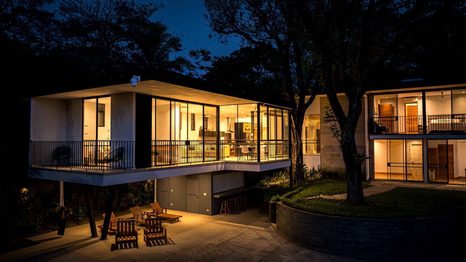Modern glass villa illuminated at night among trees