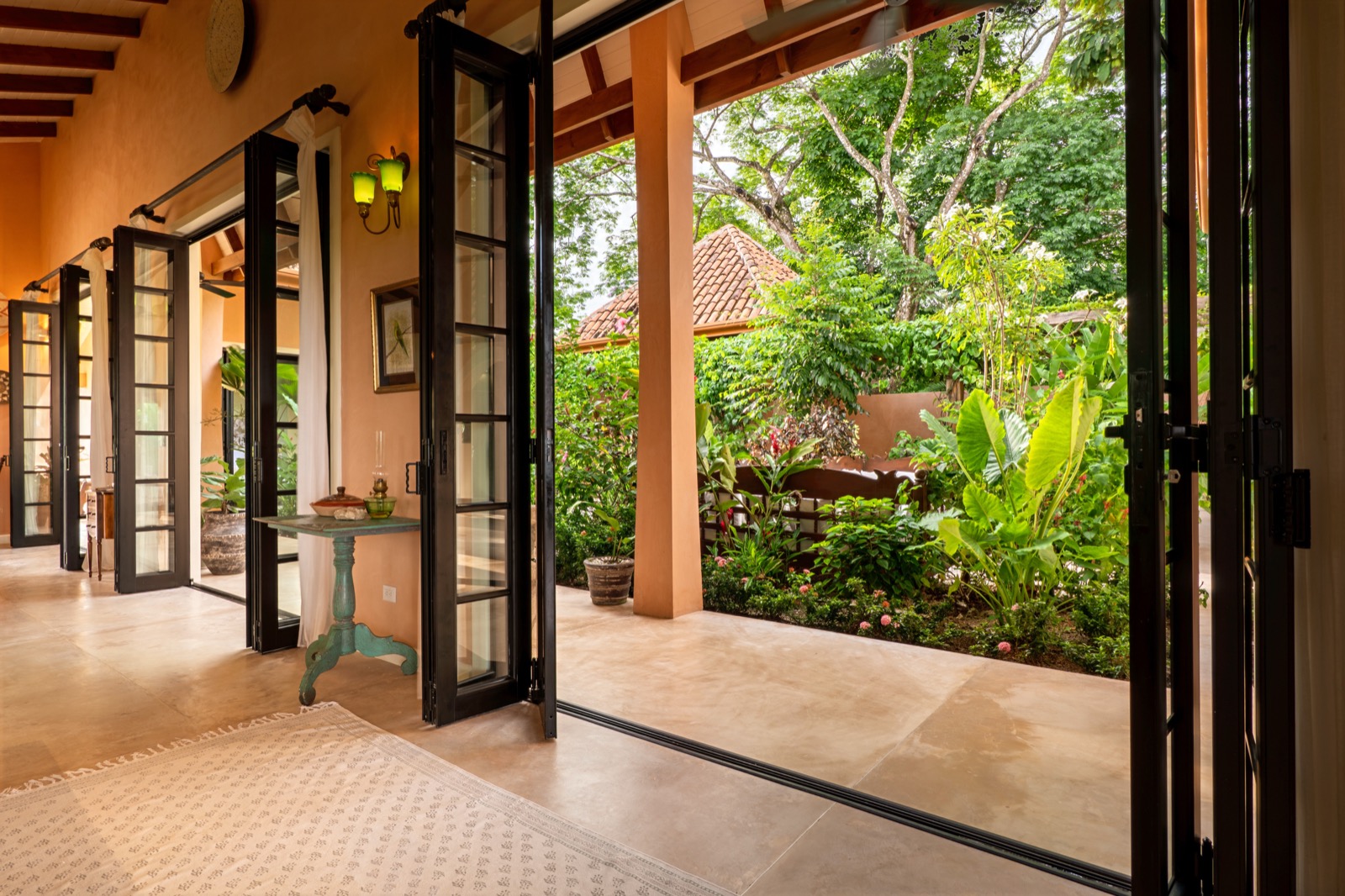 Covered corridor with open french doors to tropical garden